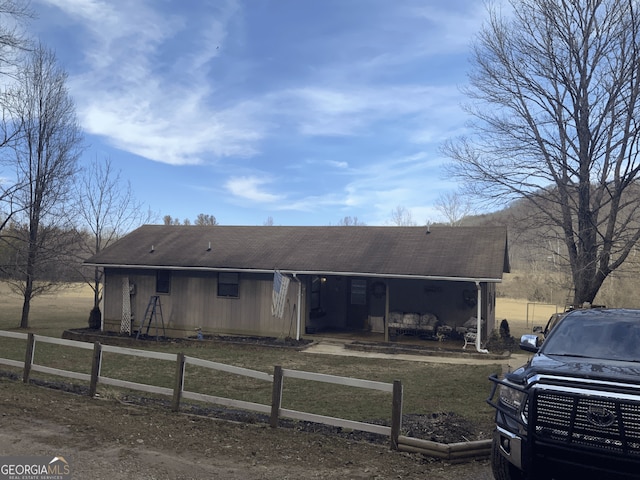 view of front of home with roof with shingles, a fenced front yard, and a porch