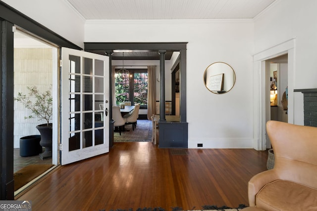 corridor featuring wood finished floors, crown molding, baseboards, and a chandelier