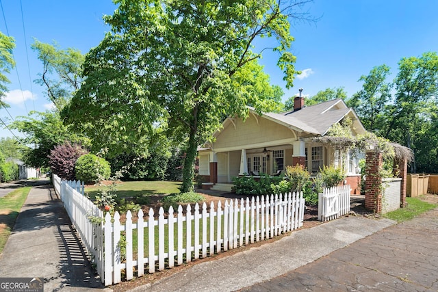 view of front facade with a fenced front yard, ceiling fan, a porch, and a chimney