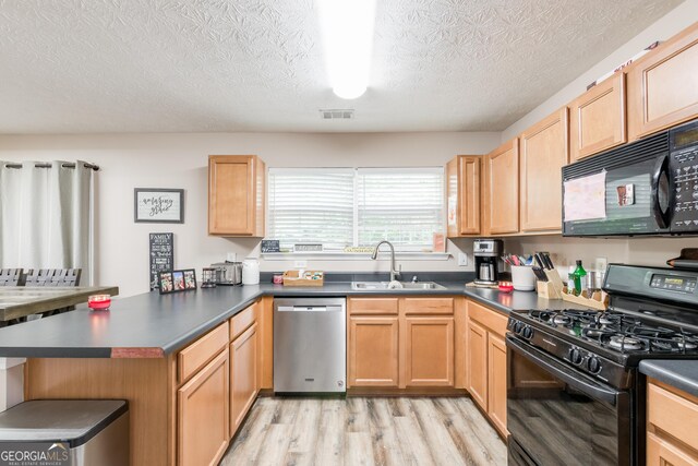 314 Meadows Ln, Canton, GA 30114 - kitchen with black appliances, a sink, a peninsula, light wood-type flooring, and dark countertops