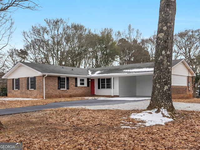 single story home featuring an attached carport, brick siding, and aphalt driveway