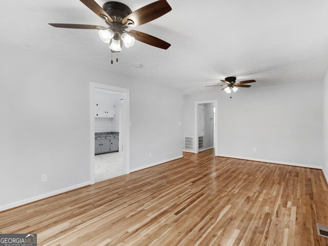 unfurnished living room with light wood-style floors, a ceiling fan, baseboards, and visible vents