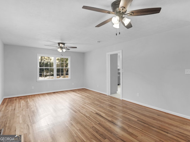 interior space with a ceiling fan, baseboards, and light wood-style floors