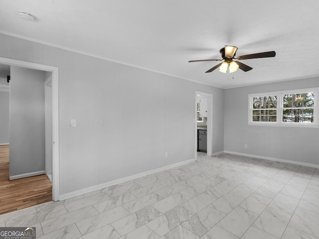 empty room with ceiling fan, ornamental molding, baseboards, and marble finish floor