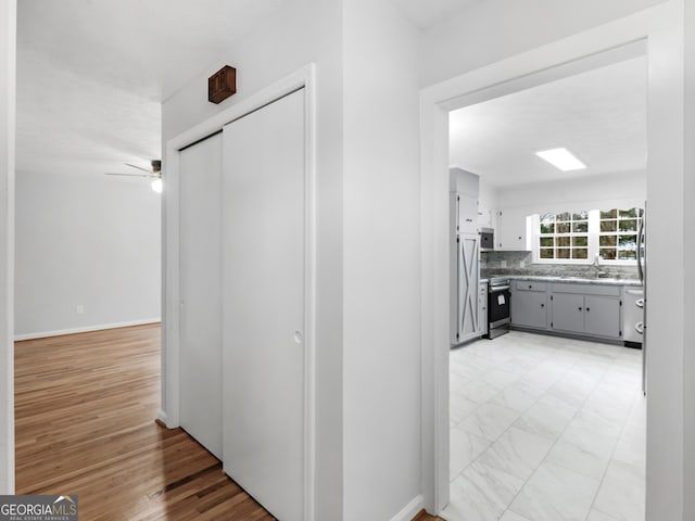 corridor featuring a sink and light wood-type flooring