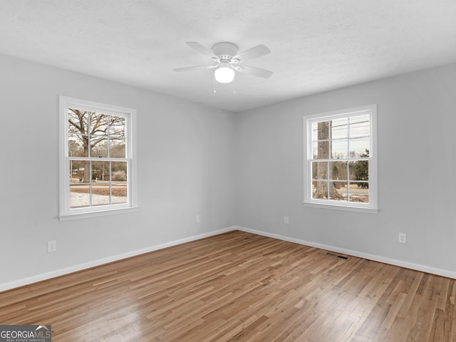 unfurnished room with visible vents, wood finished floors, baseboards, a textured ceiling, and a ceiling fan