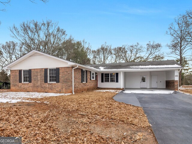single story home featuring brick siding, an attached carport, and concrete driveway