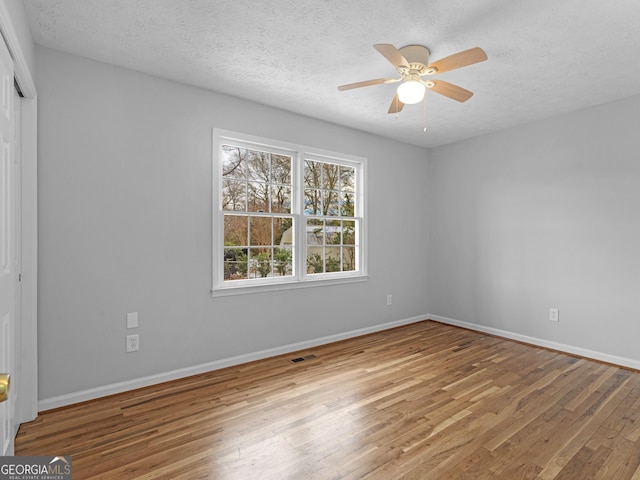 empty room with a textured ceiling, ceiling fan, and wood finished floors
