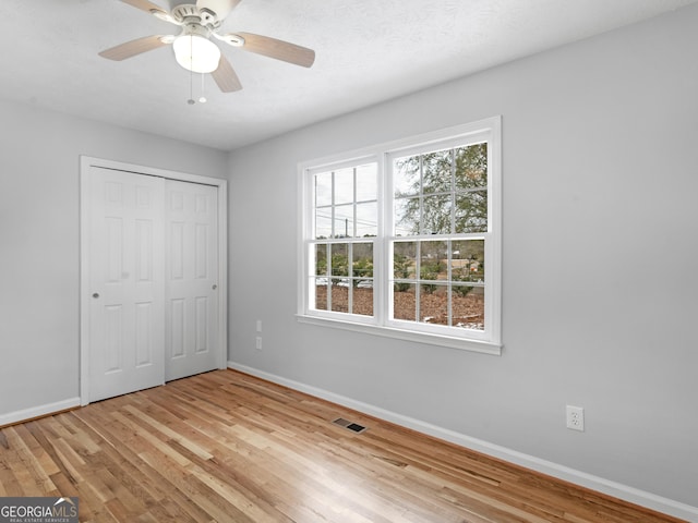 unfurnished bedroom with baseboards, light wood finished floors, and a closet