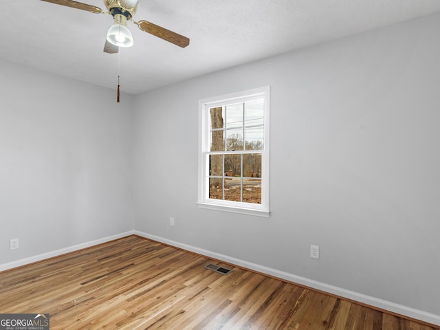 spare room with baseboards, ceiling fan, wood-type flooring, and visible vents