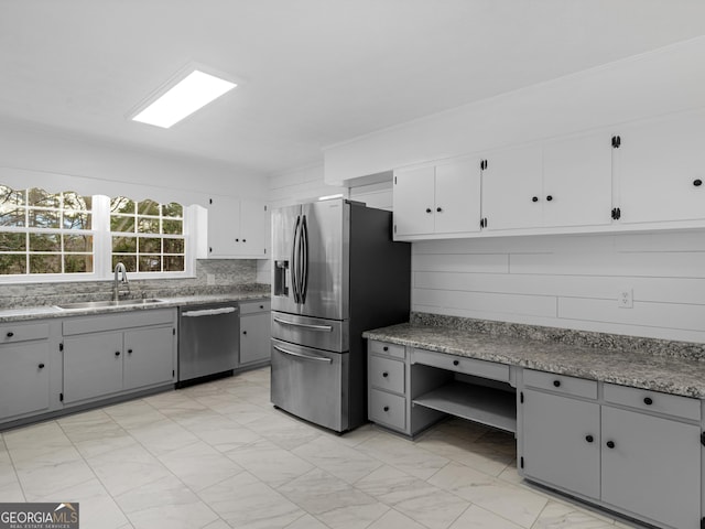 kitchen featuring white cabinets, gray cabinets, appliances with stainless steel finishes, and a sink