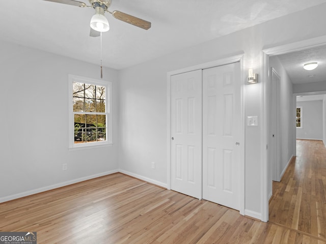 interior space with a ceiling fan, baseboards, light wood-style flooring, and a closet