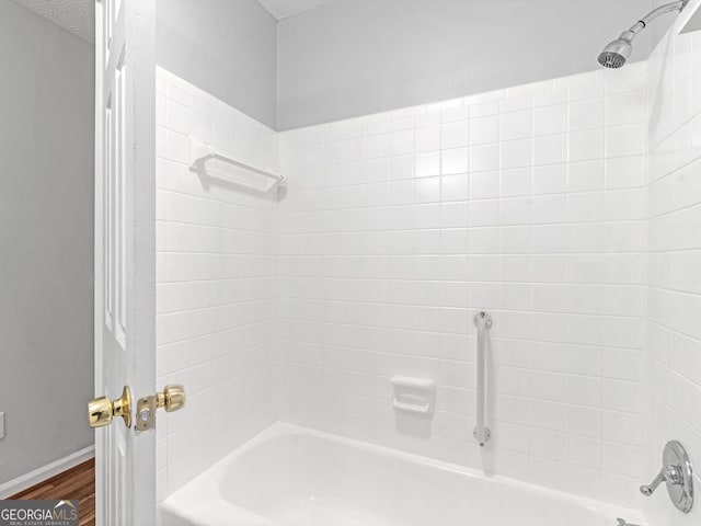 bathroom with baseboards, shower / bathing tub combination, and wood finished floors