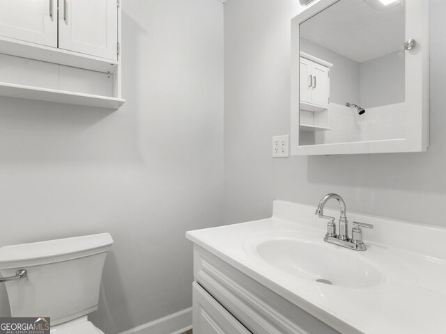 bathroom featuring toilet, baseboards, and vanity