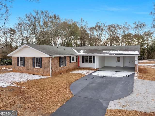 view of front facade with roof with shingles, a carport, aphalt driveway, and brick siding
