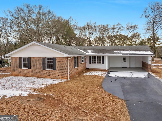 ranch-style home featuring concrete driveway, brick siding, roof with shingles, and a carport