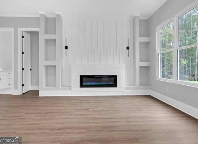 3312 Mill Forest Dr, Conyers, GA 30094 - unfurnished living room with crown molding, baseboards, built in shelves, and wood finished floors