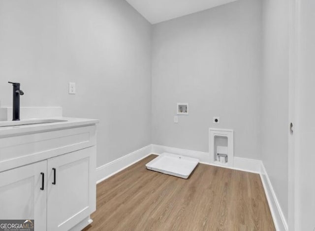 3312 Mill Forest Dr, Conyers, GA 30094 - laundry room with electric dryer hookup, cabinet space, a sink, light wood finished floors, and hookup for a washing machine