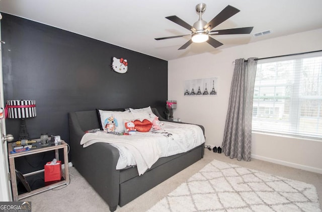carpeted bedroom featuring ceiling fan, visible vents, baseboards, and an accent wall