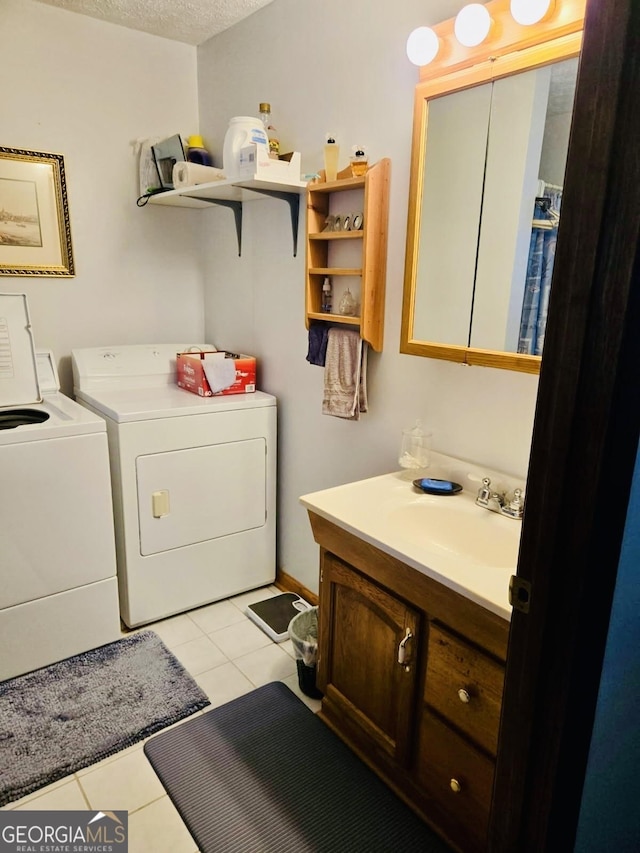 laundry room with laundry area, light tile patterned flooring, a textured ceiling, separate washer and dryer, and a sink