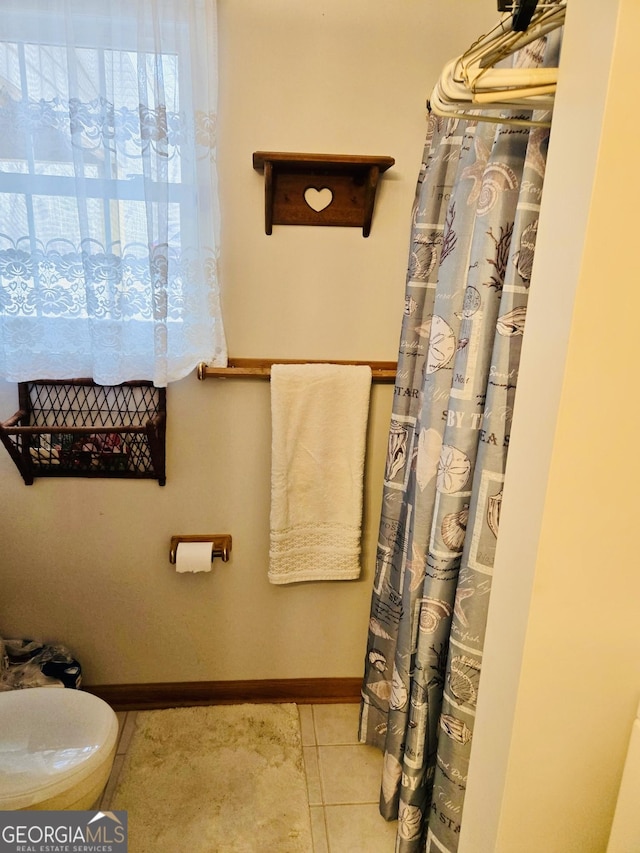 bathroom featuring baseboards, tile patterned floors, toilet, and a shower with curtain