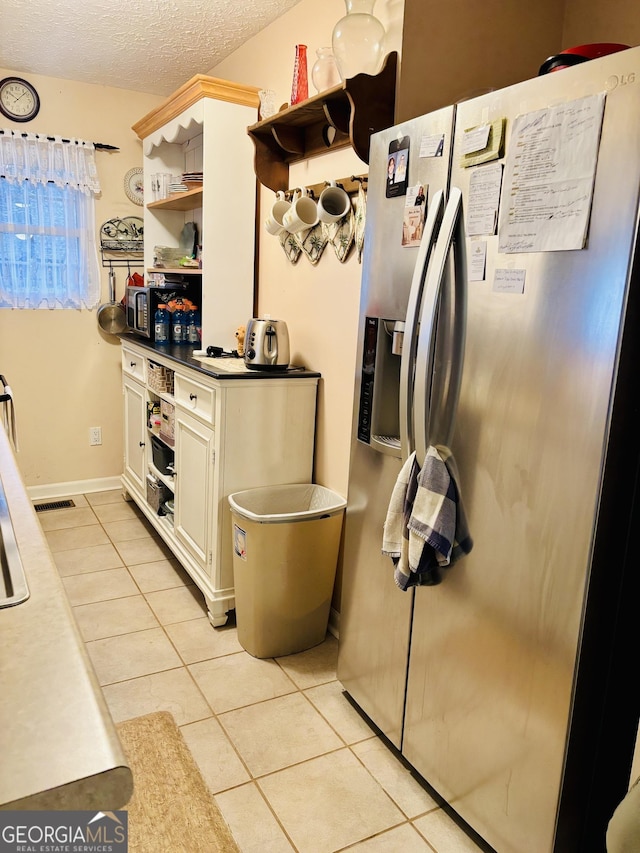 kitchen featuring stainless steel refrigerator with ice dispenser, a textured ceiling, visible vents, open shelves, and light tile patterned floors