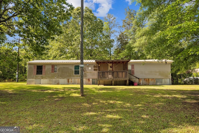 rear view of property featuring a lawn, a deck, and metal roof
