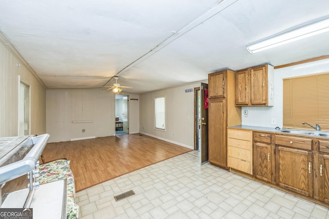 kitchen featuring visible vents, a ceiling fan, brick patterned floor, brown cabinets, and a sink