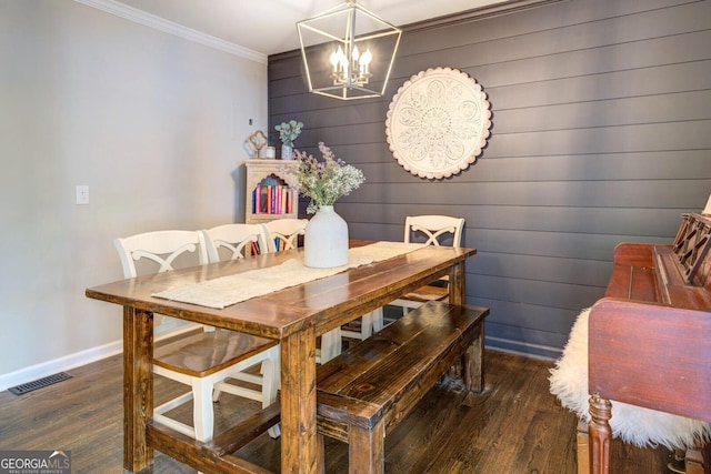 dining space with crown molding, a notable chandelier, baseboards, wood finished floors, and visible vents