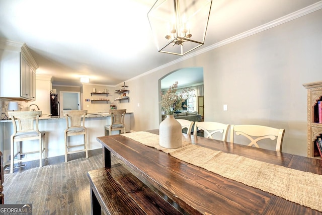 dining room featuring crown molding, arched walkways, an inviting chandelier, and dark wood-type flooring