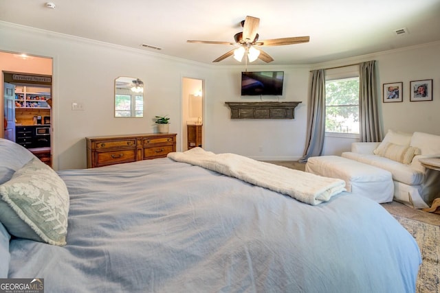 bedroom with a walk in closet, ornamental molding, ceiling fan, and visible vents