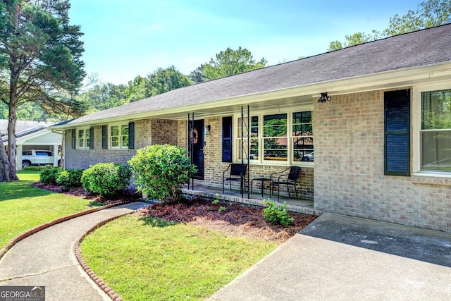 view of front of house with brick siding, covered porch, and a front yard