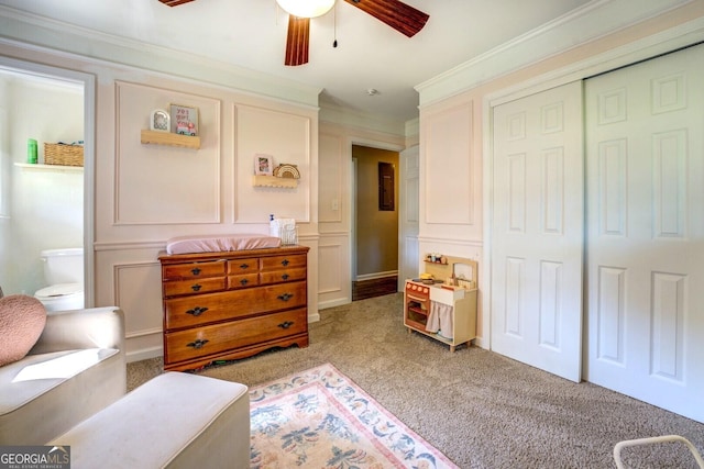 interior space with a closet, crown molding, a ceiling fan, a decorative wall, and carpet flooring