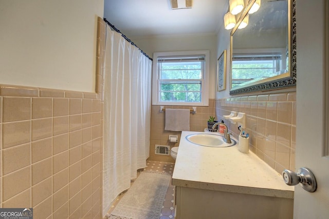 bathroom with crown molding, vanity, visible vents, toilet, and tile walls