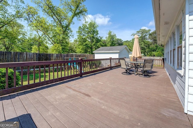 deck with an outdoor structure, a fenced backyard, a storage unit, and outdoor dining space