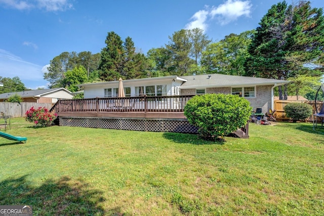 back of property featuring fence, a trampoline, a lawn, and a deck