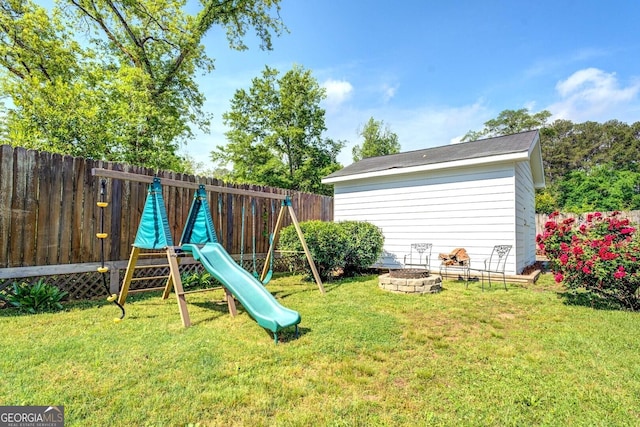 view of playground with a fenced backyard, a fire pit, and a yard