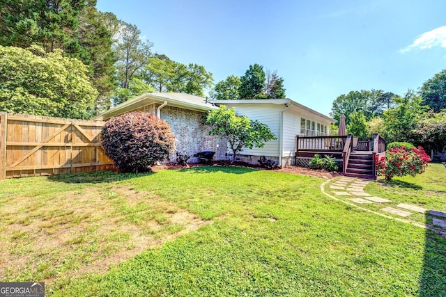 exterior space with a lawn, a deck, and fence