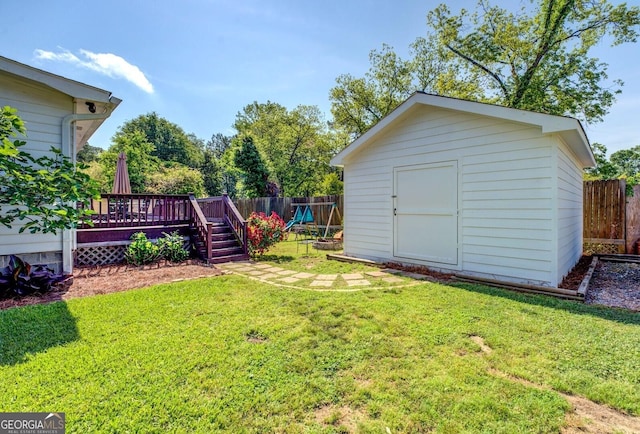 view of yard featuring a storage shed, a wooden deck, an outdoor structure, and a fenced backyard