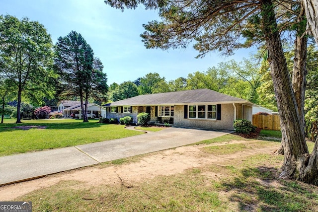 ranch-style house with fence, driveway, a front lawn, and brick siding