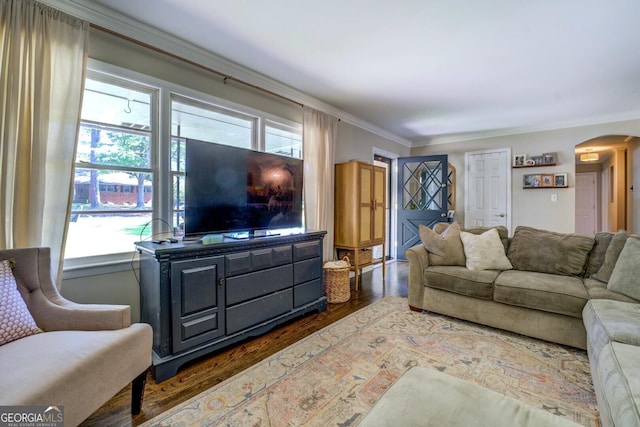 living room with arched walkways, ornamental molding, and wood finished floors