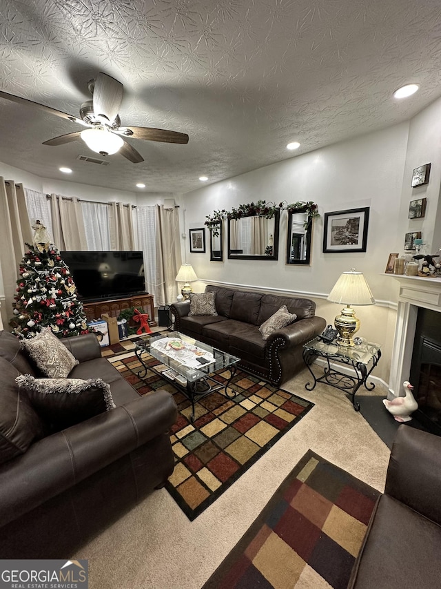 carpeted living room featuring a fireplace, ceiling fan, visible vents, and recessed lighting