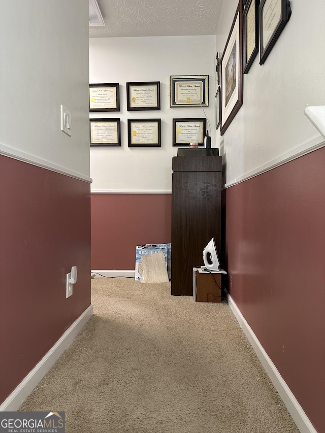 hall featuring baseboards and carpet
