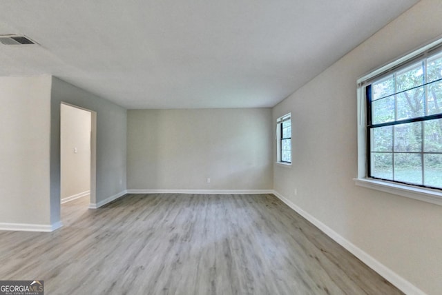 unfurnished room with baseboards, visible vents, and wood finished floors