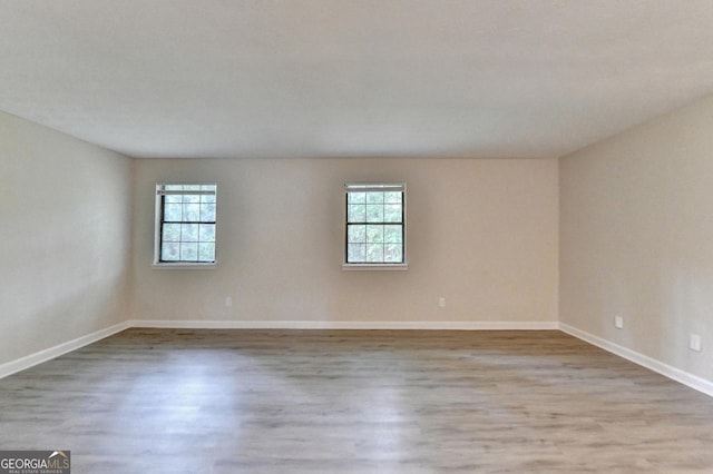 spare room with baseboards, wood finished floors, and a wealth of natural light