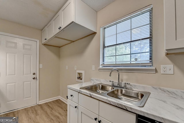 interior space featuring a sink, baseboards, light wood-style flooring, and white cabinetry