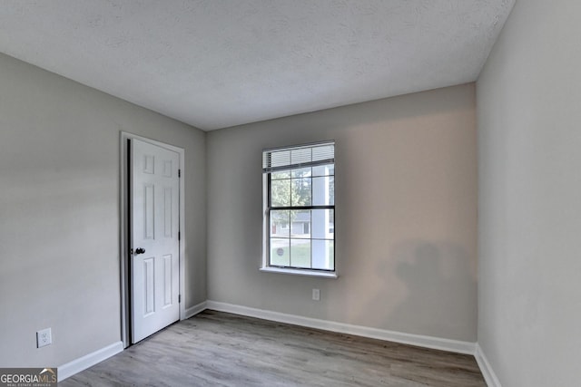 unfurnished room featuring baseboards, a textured ceiling, and wood finished floors