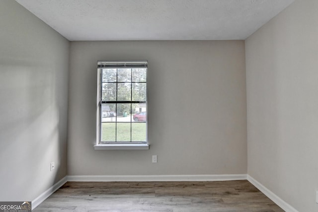 empty room with plenty of natural light, baseboards, and wood finished floors