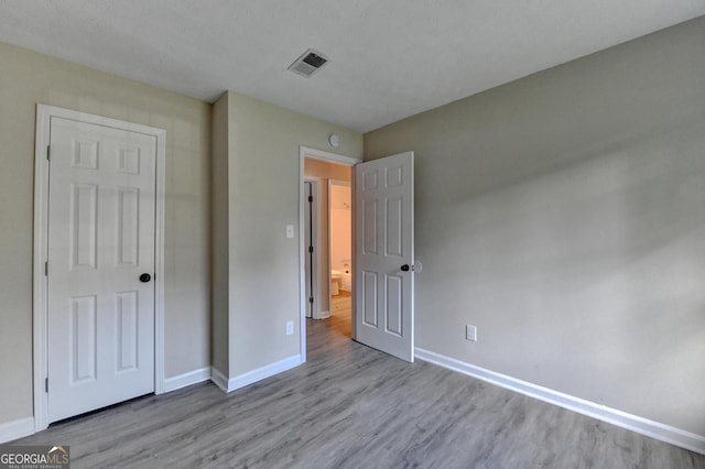 unfurnished bedroom with baseboards, wood finished floors, and visible vents