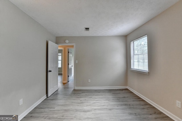 spare room with baseboards, wood finished floors, and visible vents